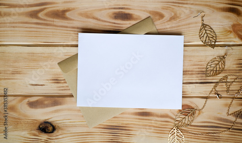 White greeting card mock up on the wooden table with craft envelope, place for a text.