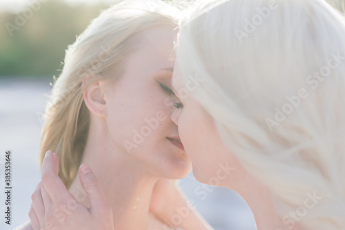 Beautiful lesbian couple walking on sand along river bank on their wedding day