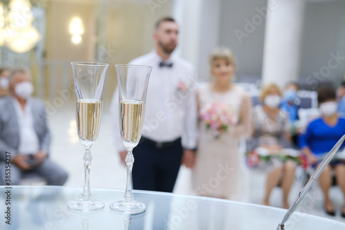 Two glasses of champagne on the table on the wedding ceremony, happy groom and bride. .