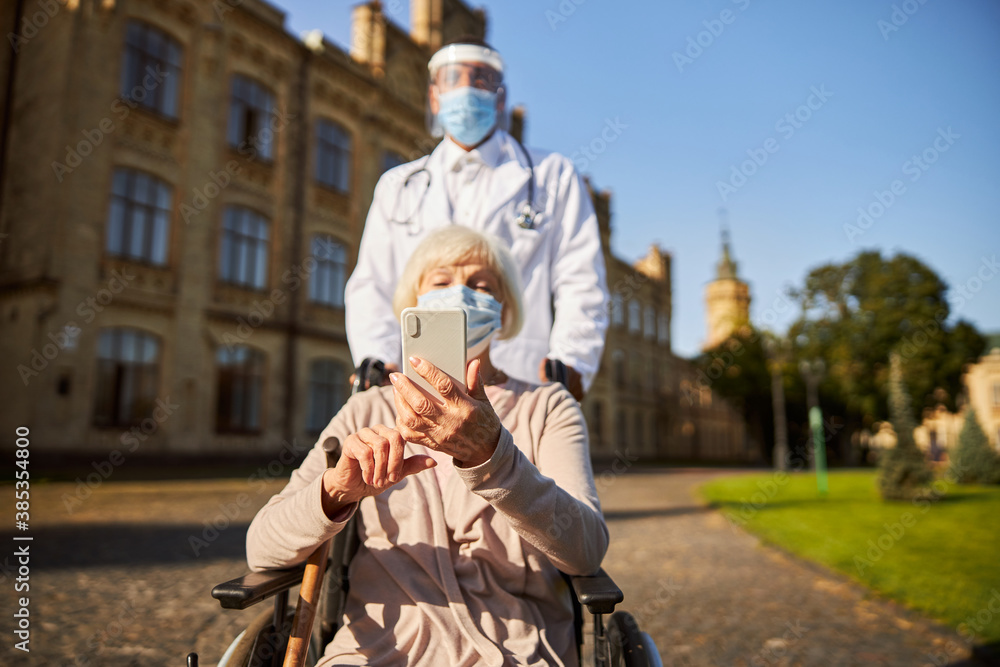 Care home resident with modern gadget outdoors
