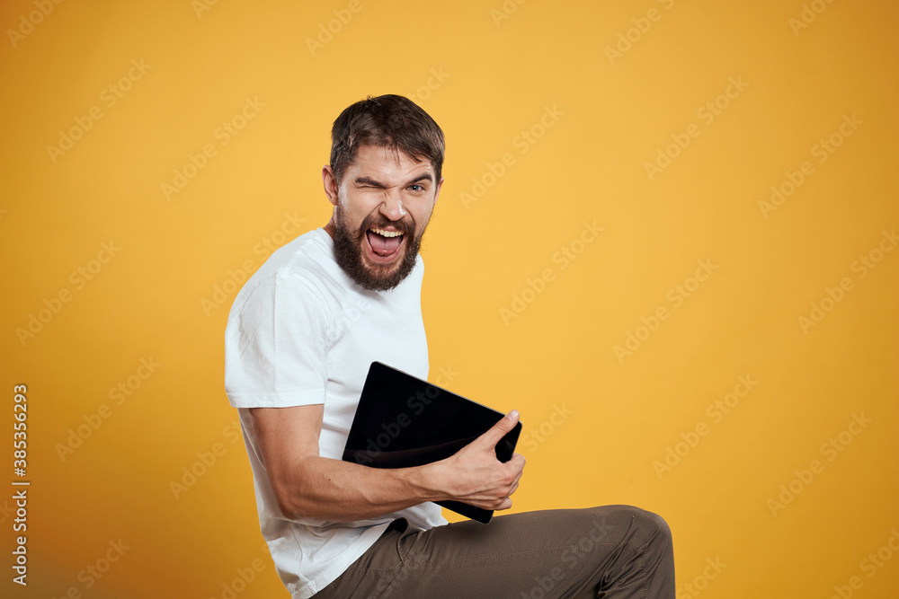 Man with a tablet on a yellow background in a white t-shirt new technologies businessman touch screen touchpad Man with a tablet on a yellow background in a white t-shirt new technologies businessman touch screen touchpad