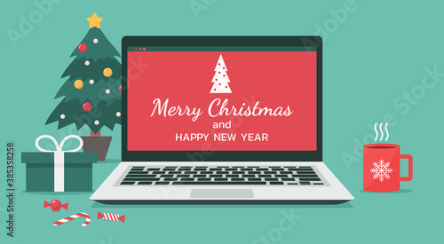 laptop with merry Christmas and happy new year lettering for online celebration holiday at home decorate with gifts, candy, cup, and Christmas tree, vector flat illustration