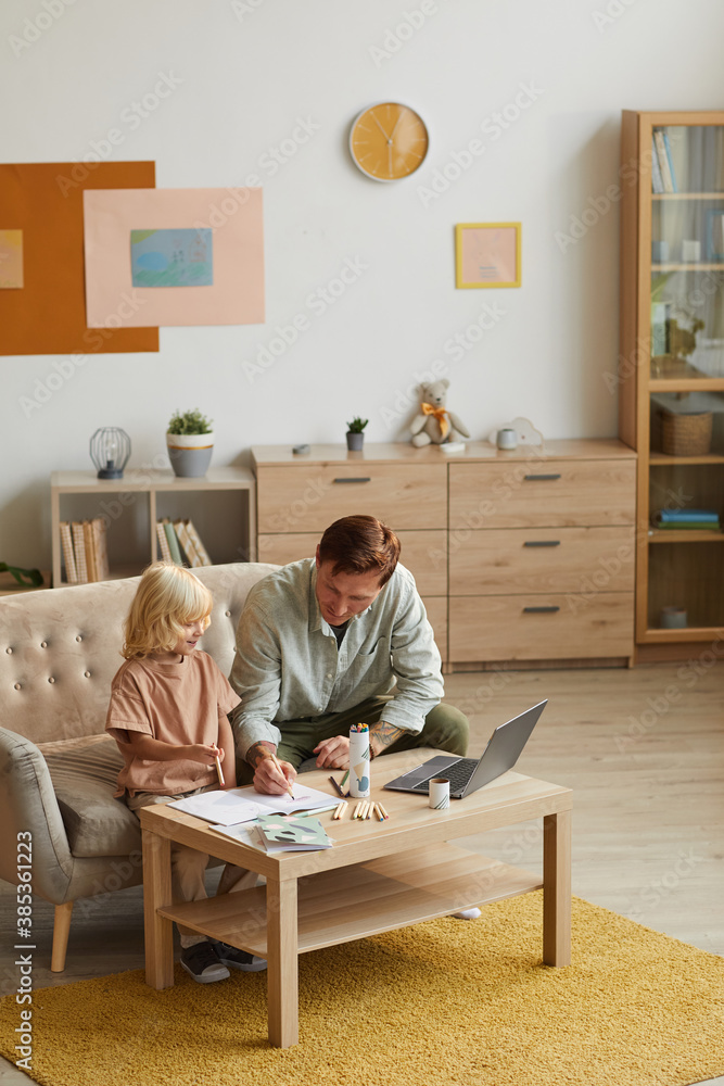 Father drawing together with his little son at the table during leisure time at home Father drawing together with his little son at the table during leisure time at home
