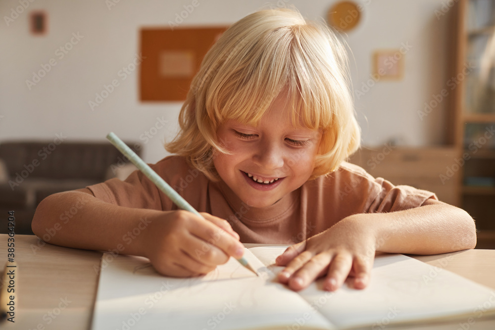 Child with blond hair writing the report in note book he doing homework after school Child with blond hair writing the report in note book he doing homework after school