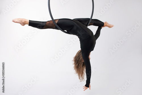 A female gymnast performing exercises on an air ring (hoop) on a gray background