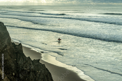 A single surfer surveys the ocean in Montauk, NY
