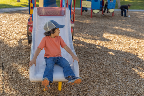 Photography A casually dressed little boy looks to his left when he reaches the bottom of the slide