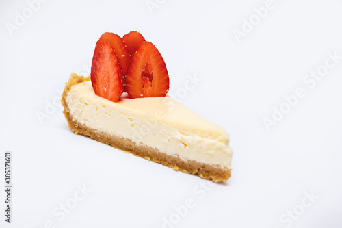 Piece of cheesecake with fresh strawberries on white plate
