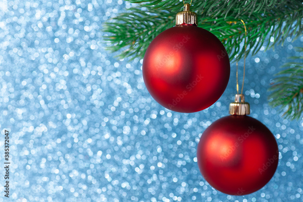 two red shiny ball on a new year tree branch on a blue blurred background, mock up. two red shiny ball on a new year tree branch on a blue blurred background, mock up.