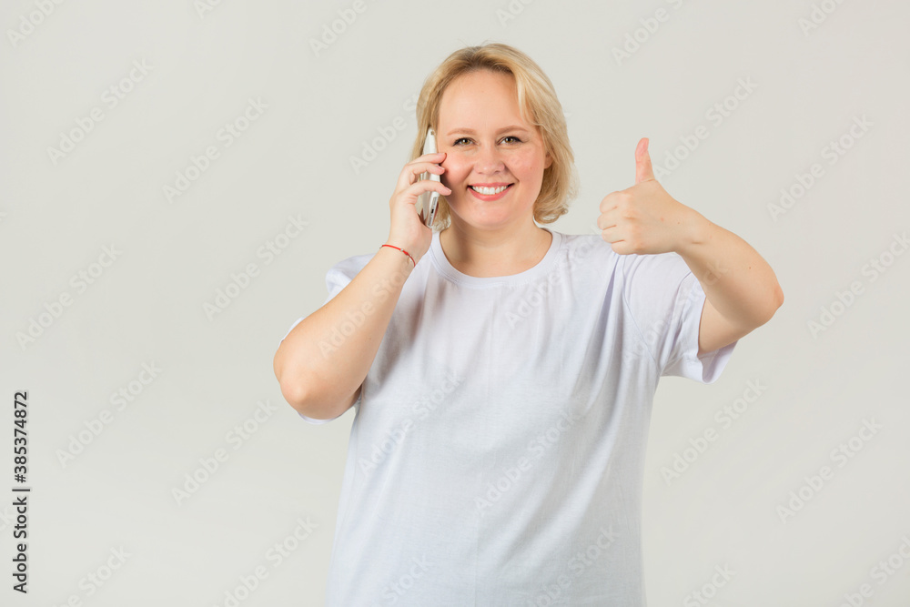 beautiful young plump female in a white t-shirt with a phone in her hand beautiful young plump female in a white t-shirt with a phone in her hand