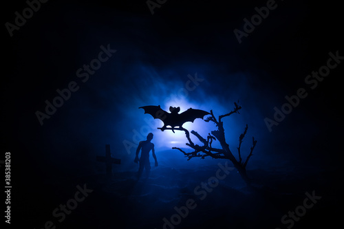 Scary view of zombies at cemetery dead tree, moon, church and spooky cloudy sky with fog, Horror Halloween concept with glowing pumpkin. Selective focus