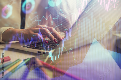 Double exposure of woman hands typing on computer and financial graph hologram drawing. Stock market analysis concept.