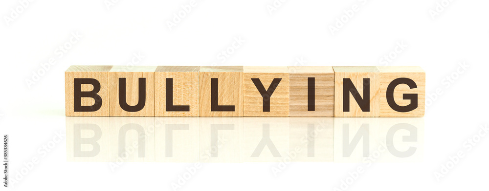 Wooden Blocks with the text: Bullying. The text is written in black letters and is reflected in the mirror surface of the table. New business relaunch startup concept