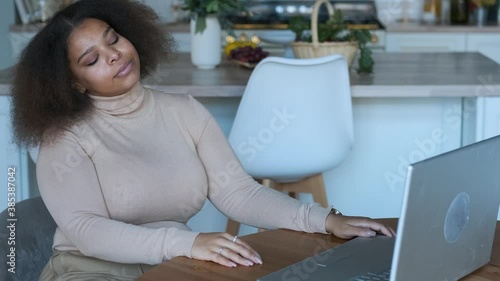 remote work black woman bored sitting at the table with laptop at home
