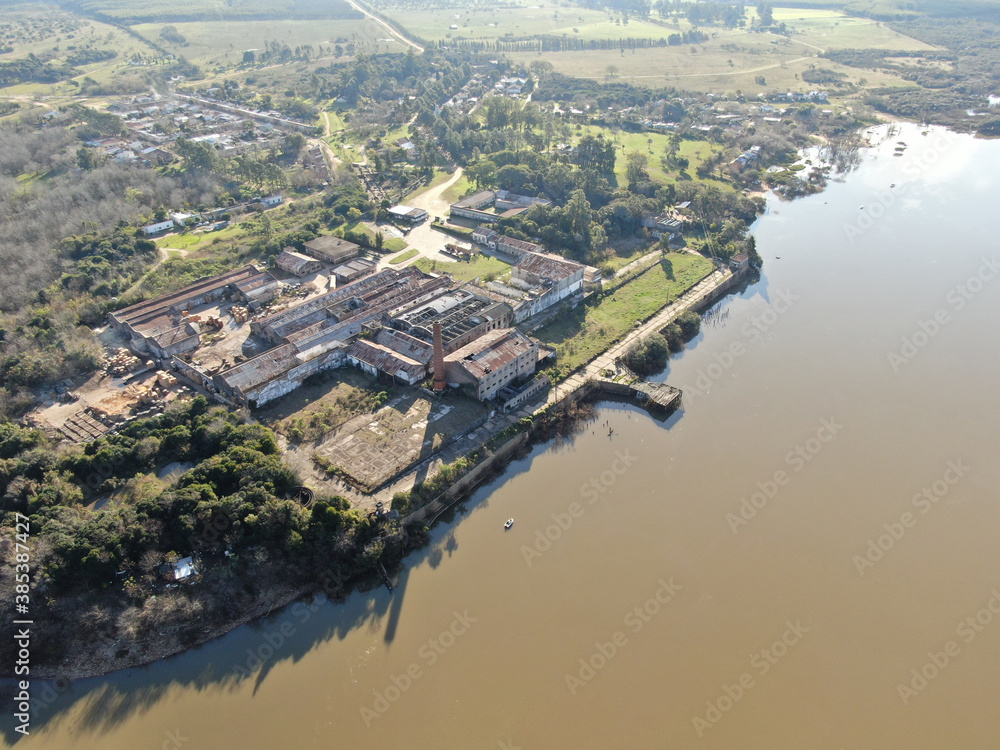 Vista aérea desde un dron de una fábrica del año 1865 abandonada y su muelle que da al río. 