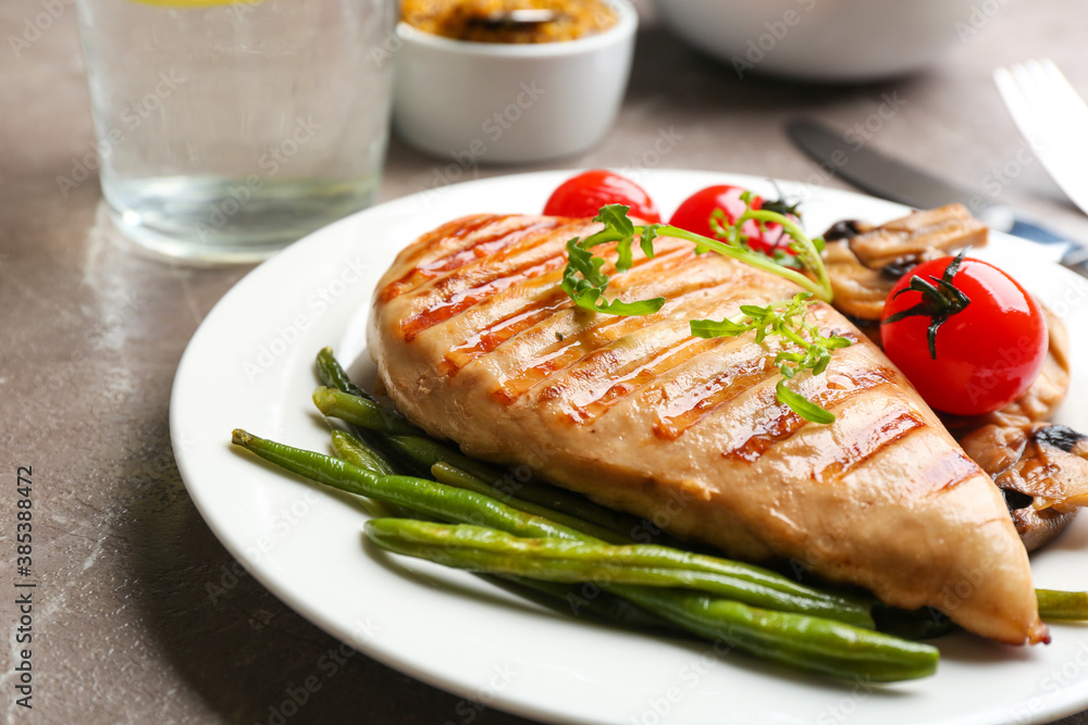 Tasty grilled chicken fillet with green beans, tomatoes and arugula on table, closeup