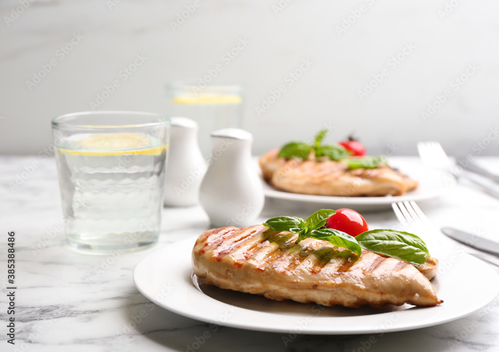 Tasty grilled chicken fillet with green basil and tomato on white marble table