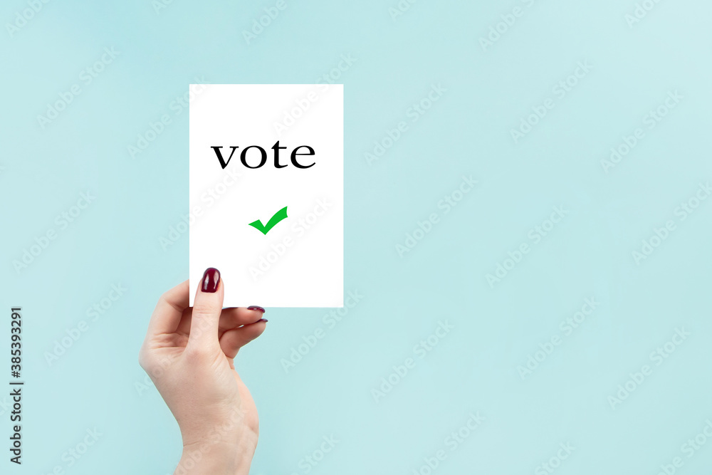 Concept of voting by mail, US elections. A woman holds a sign on a blue background. Concept of voting by mail, US elections. A woman holds a sign on a blue background.