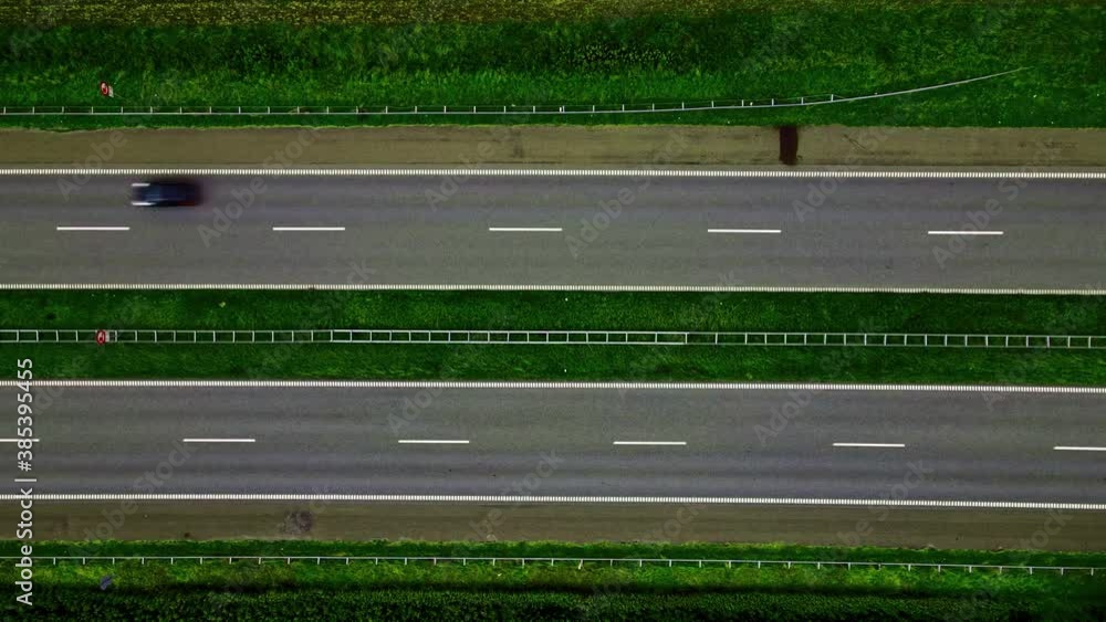 Cars driving by on a freeway with green grass on the sides. Top down aerial footage. Cars driving by on a freeway with green grass on the sides. Top down aerial footage.