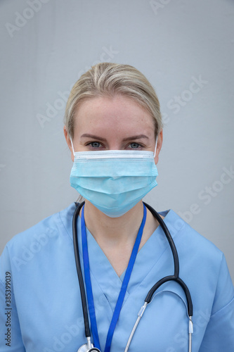 Portrait of female health worker wearing face mask against grey background