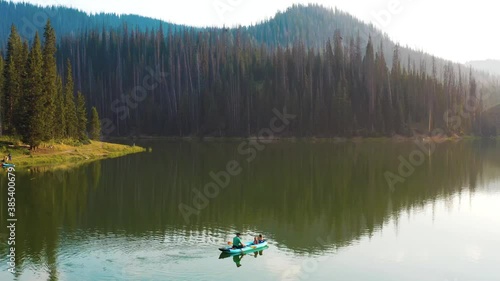 Aerial shot of a man and his two daughters fishing in a canoe on a mountain lake during golden hour photo