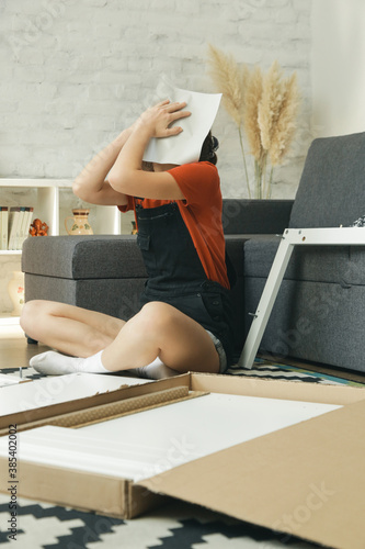 Annoyed woman having problem while assembling furniture by herself
 photo