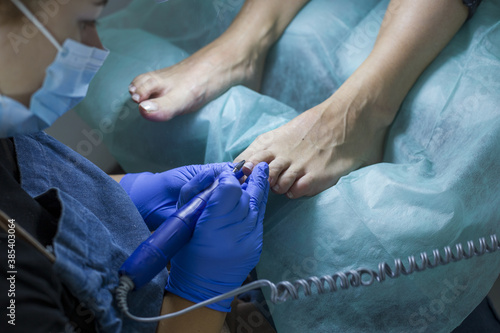 Close up of doctor in gloves making procedure for foot. Pedicure in beauty spa salon. Beautician polishing nails.