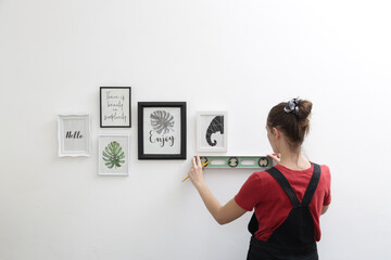 Woman arranging picture frames on wall in new house, diy home improvement concept