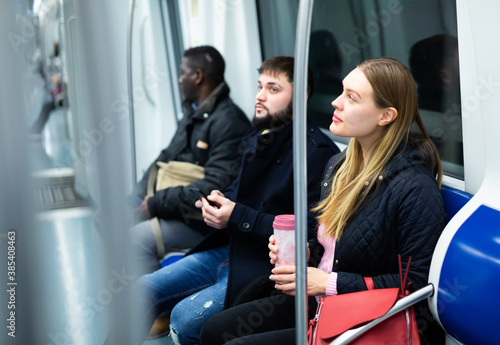 Portrait of different adult people in warm overcoats during trip in metro train © JackF