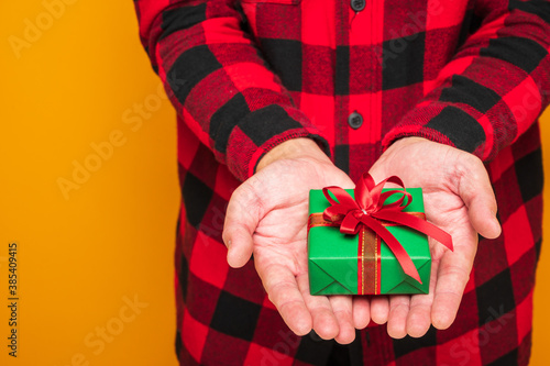 Merry christmas and Happy new year 2021 male hands holding the present gift box. Man giving the box celebrate with his birthday on isolated yellow background.