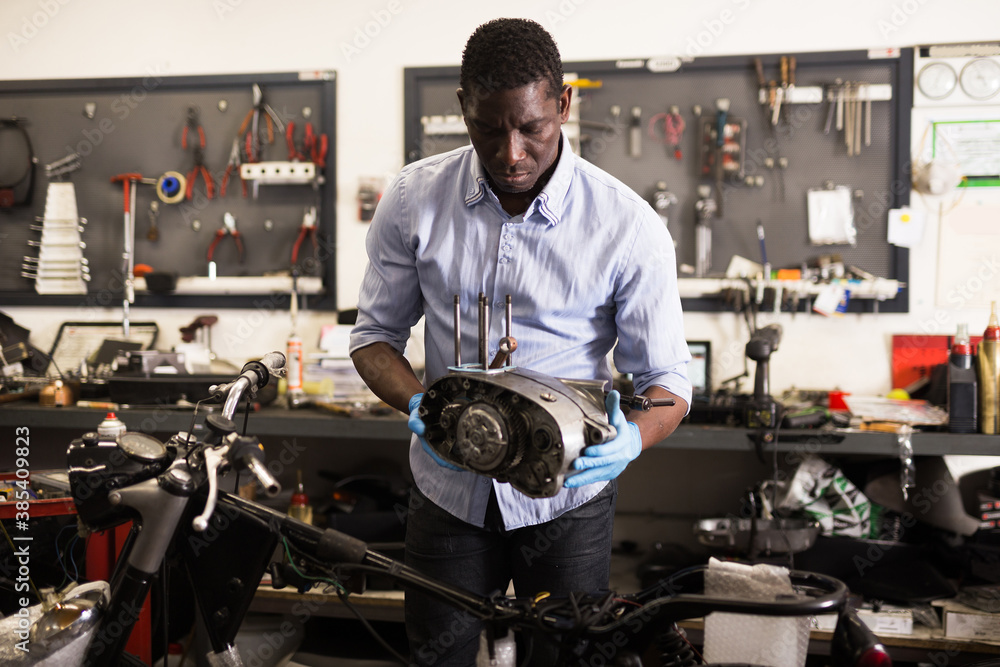 Portrait of afro american man master who is repairing motobike. High quality photo