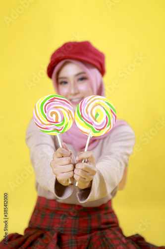 Smiling Young Woman Asian girl holding candy lollipop. Young cheerful woman with lollipop at studio background, copy space. Sweet life and sweet food.