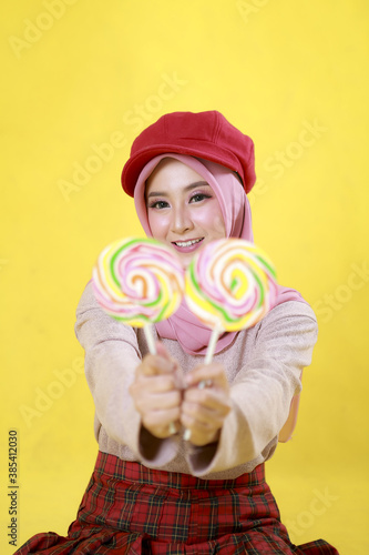 Smiling Young Woman Asian girl holding candy lollipop. Young cheerful woman with lollipop at studio background, copy space. Sweet life and sweet food.