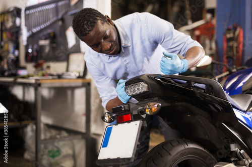 Afro american expert inspects the wheel of a motorcycle. High quality photo