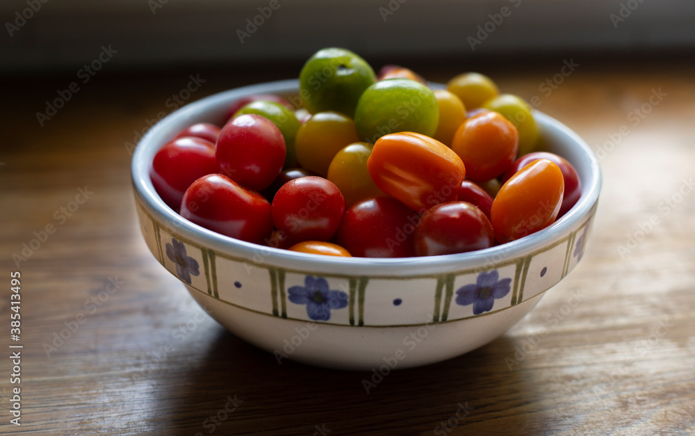 A slightly elevated view of a small white with blue patterned ceramic bowl with a colorful mix of plum and cherry tomatoes on a wooden kitchen counter
A slightly elevated view of a small white with blue patterned ceramic bowl with a colorful mix of plum and cherry tomatoes on a wooden kitchen counter