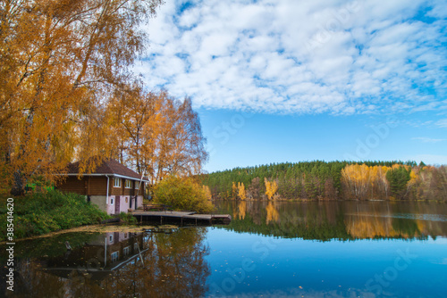 The old wooden house is located in the forest on the lake shore.