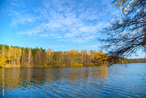 Beautiful autumn landscape with clear blue lake and yellow autumn trees.