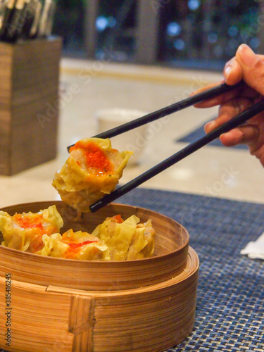 Picking up a siew mai (dim sum) with chopsticks