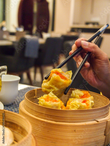Picking up a siew mai (dim sum) with chopsticks