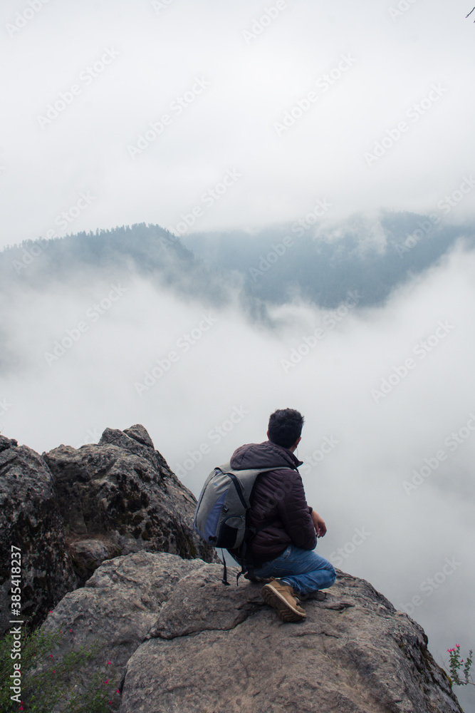 Hombre de cuclillas observando la neblina