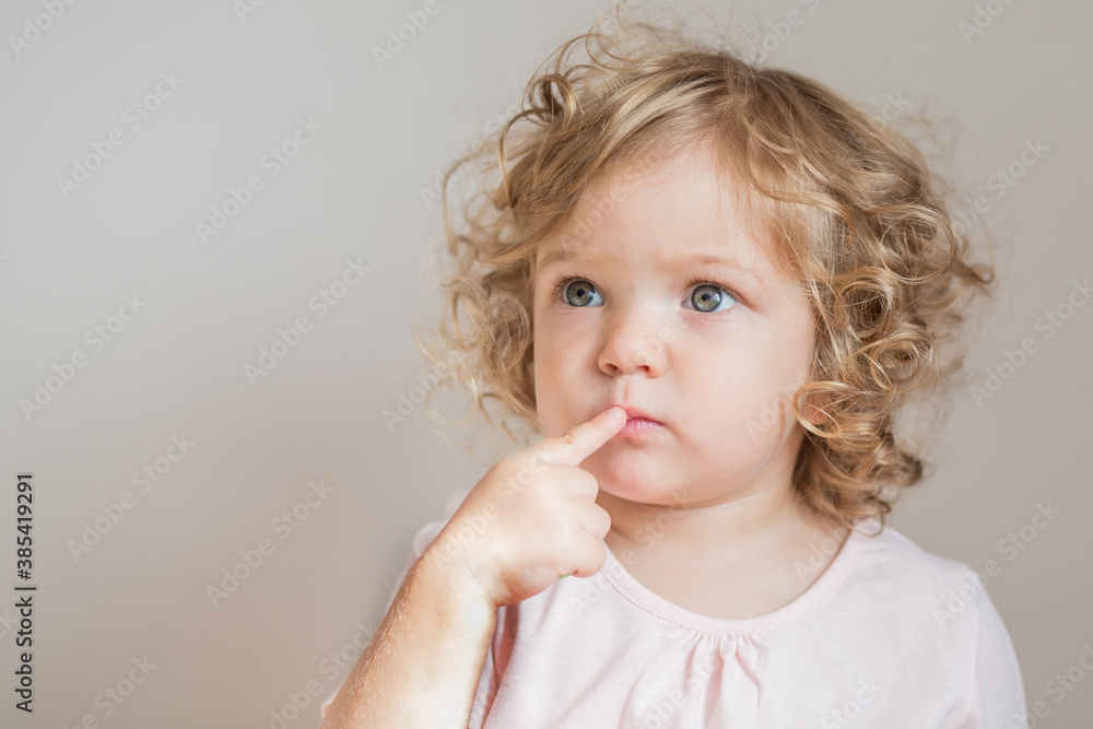 Emotional curly baby girl with finger near her face Emotional curly baby girl with finger near her face