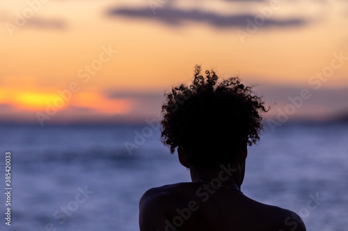 Silhouette of a man with curly hair against setting sun on an ocean coast of Maui, Hawaii