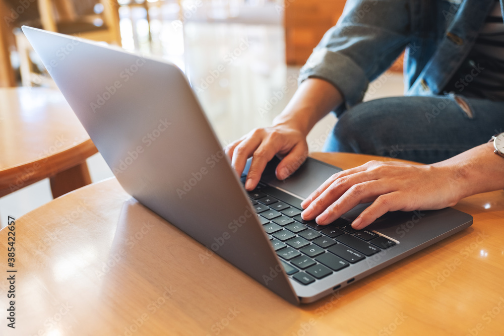 Fototapeta premium Closeup image of a woman working and typing on laptop computer keyboard on the table