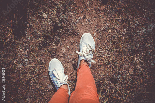 White sneakers. Legs walk along the road.