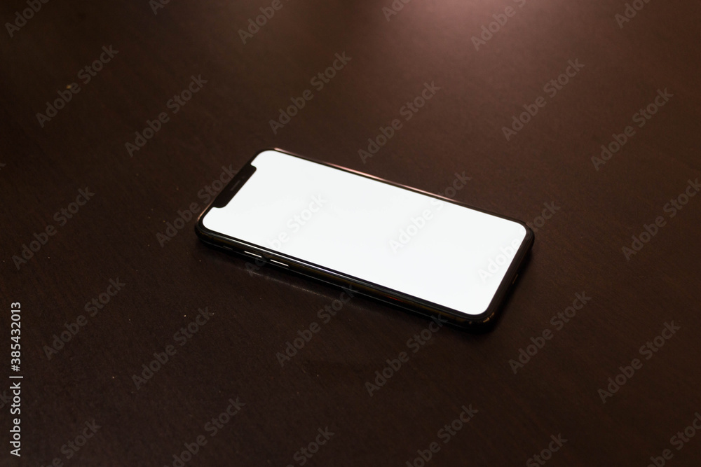 Close up black phone on brown table. Close up black phone on brown table.