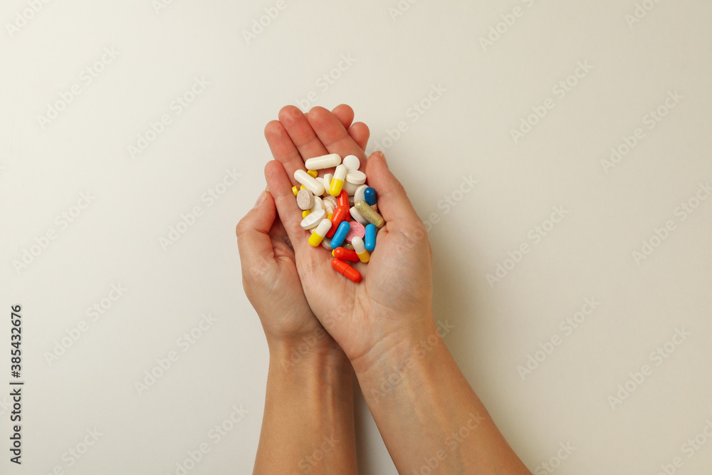 Female hands hold different pills on white background