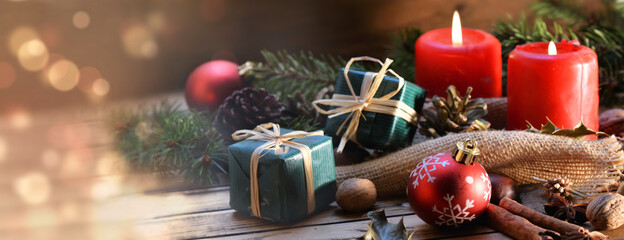 traditional christmas decoration on a wooden table with candle and gift box in panoramic view