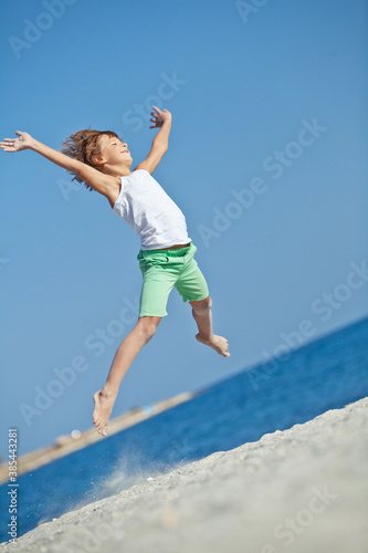 Child playing on ocean beach. Kid jumping in the waves. Sea vacation for family with kids. Little boy running on tropical beach of exotic island during summer holiday. High quality photo.