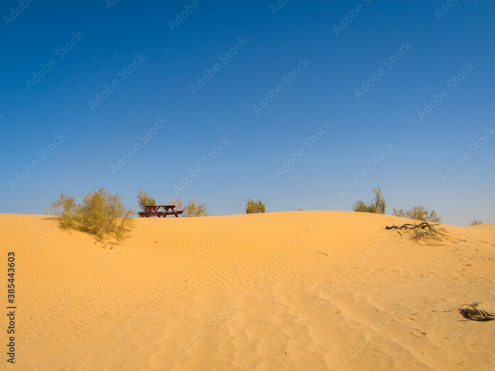 a picnic table on desert sand dunes with blue sky 
