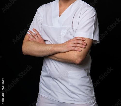a man in a white cotton medical suit, a doctor, resident or paramedic, without a face. on a dark black background © Magneya Photography